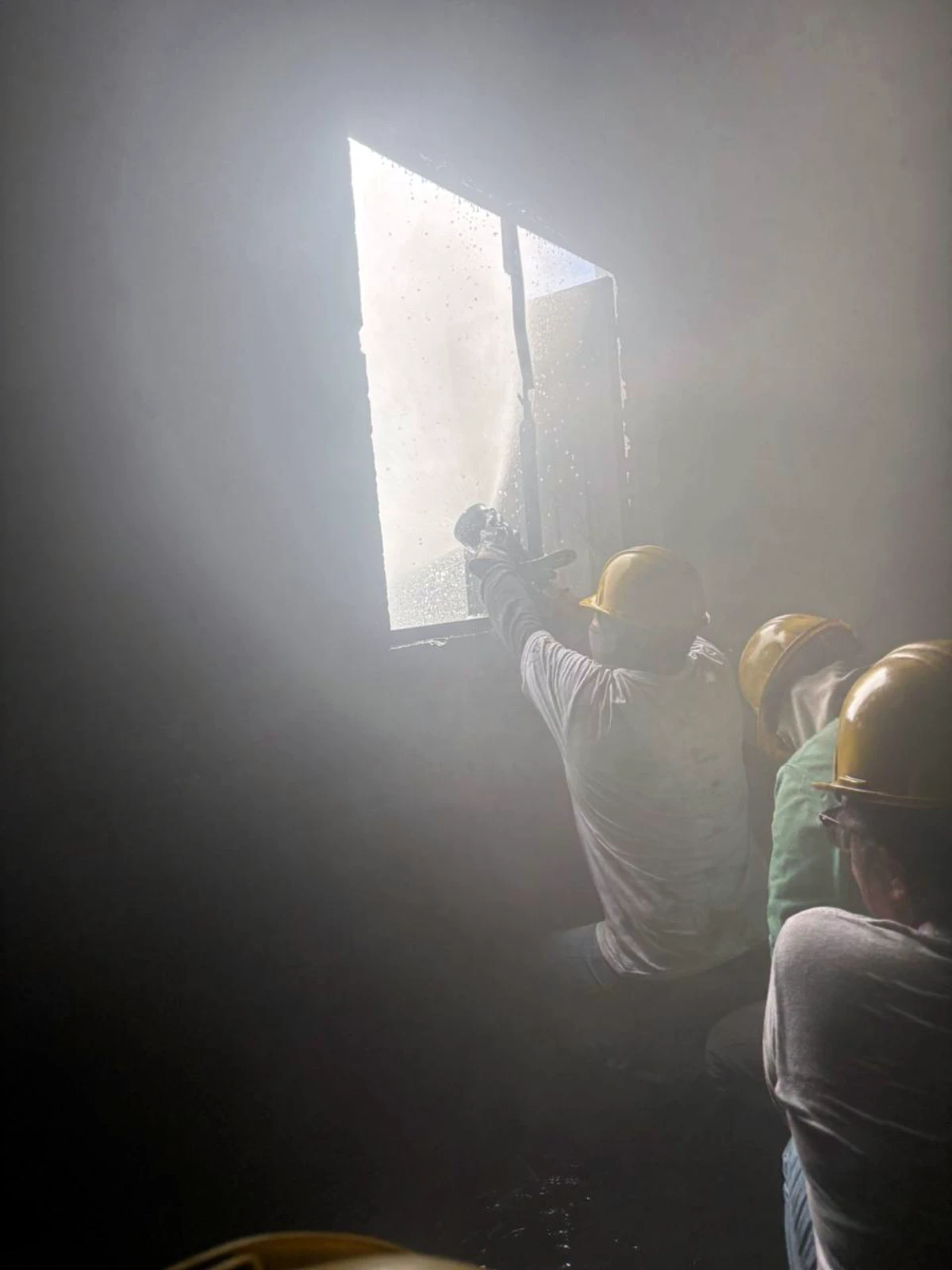 Brigada avanzando con manguera en simulador lleno de humo