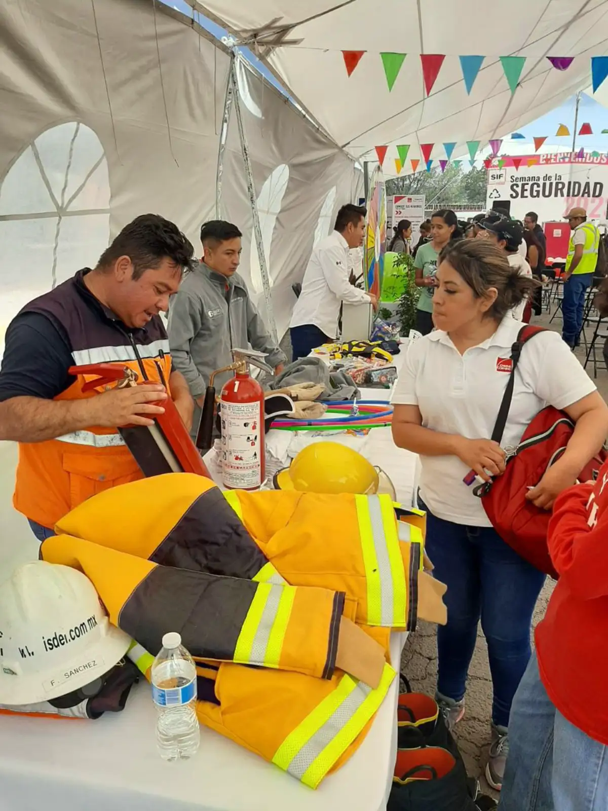 Instructor de ISDEI mostrando extintores y equipo de bombero en evento de seguridad