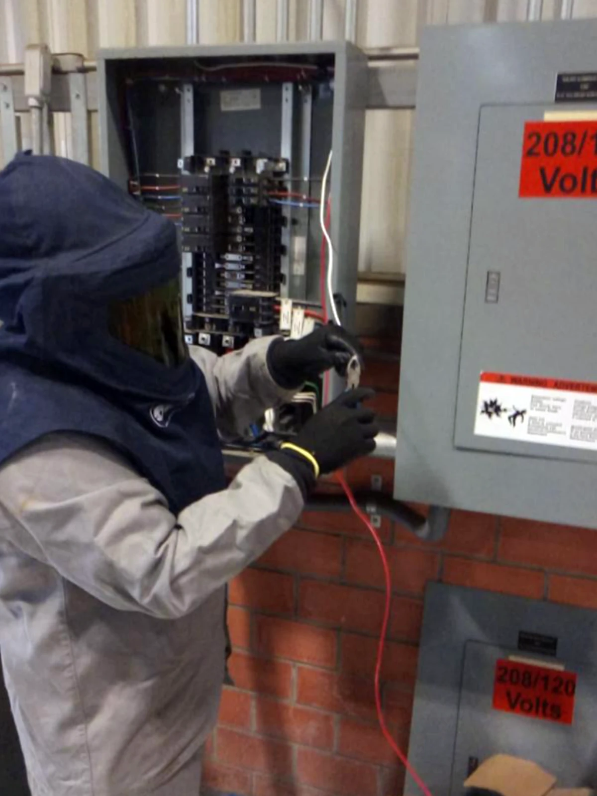 Técnico de ISDEI con equipo de protección realizando conexiones en tablero eléctrico